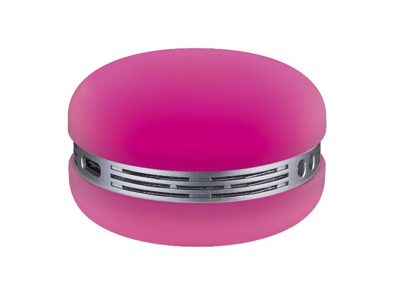 Enceinte ronde rose avec une grille de haut-parleur argentée au centre.