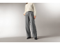Femme portant un pull en maille blanc et un pantalon large gris.