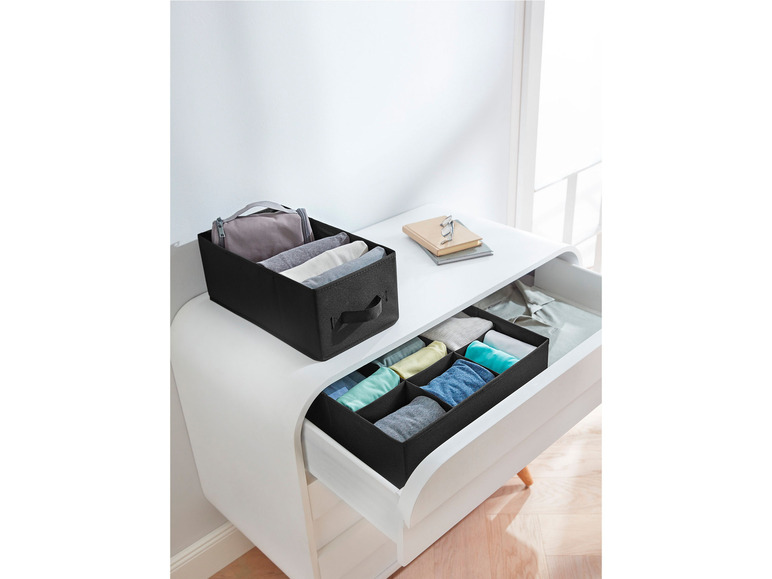Boîtes de rangement noires pour vêtements dans un tiroir blanc.