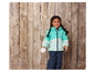 Une fille avec une veste turquoise et un pantalon bleu tient une boule de neige.