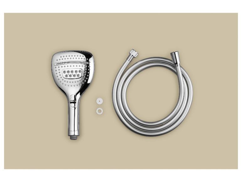 Une douchette chromée, un flexible et deux rondelles blanches sur fond beige.