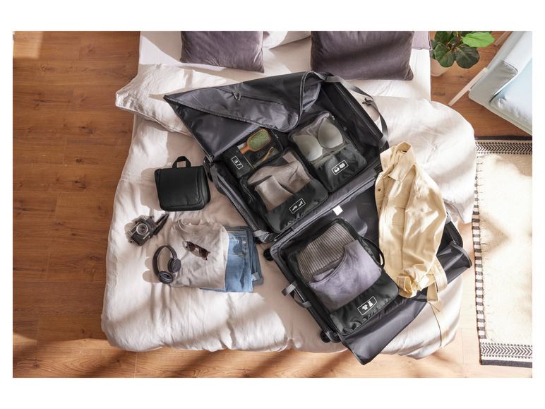 Une valise ouverte avec des vêtements, une trousse de toilette et d'autres articles de voyage.
