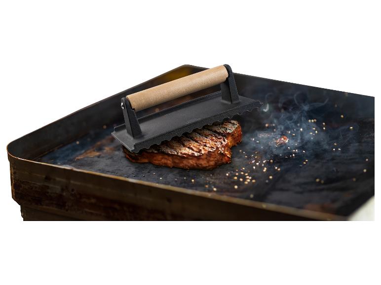 Steak grillé sur une plaque chauffante avec une presse à steak.