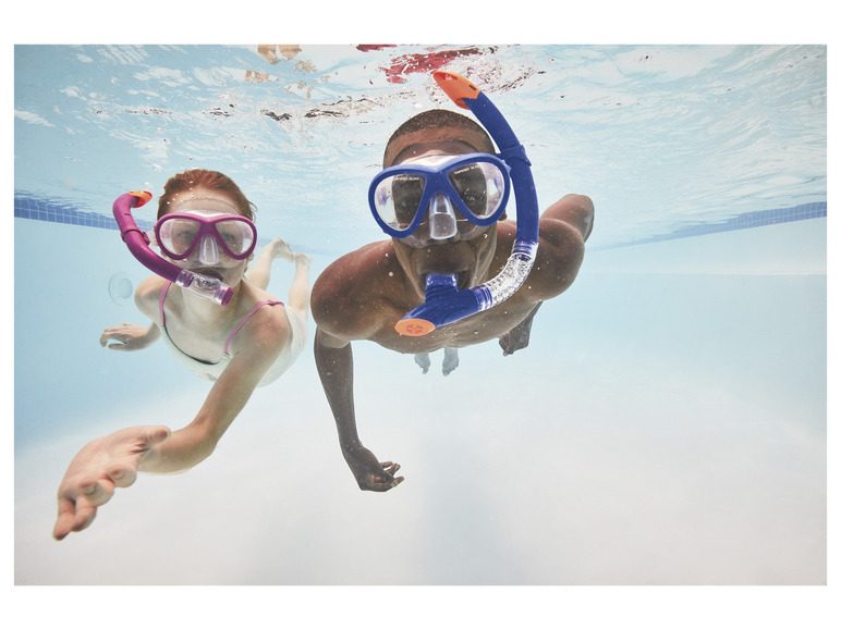 Deux personnes avec des masques de plongée et des tubas nagent sous l'eau dans une piscine.