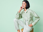 Une femme en veste en jean et pantalon vert, souriant.