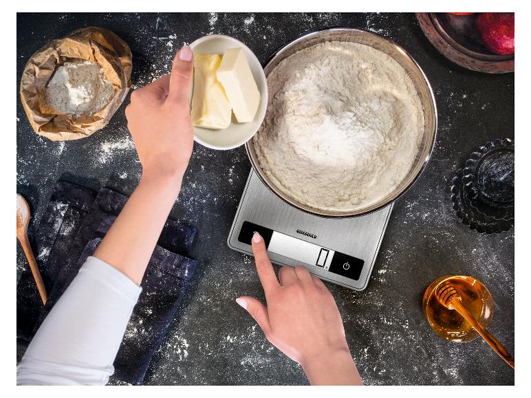 Vue de dessus des mains tenant du beurre et utilisant une balance de cuisine avec de la farine