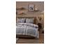 Chambre avec literie à carreaux gris, blanc et rouge, meubles en bois et étagères avec bougies.