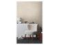Une pièce douillette avec un papier peint beige texturé, un fauteuil moelleux et une décoration minimaliste.