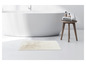 Un tapis de bain blanc dans la salle de bain, à côté d'une baignoire et d'un tabouret en bois.