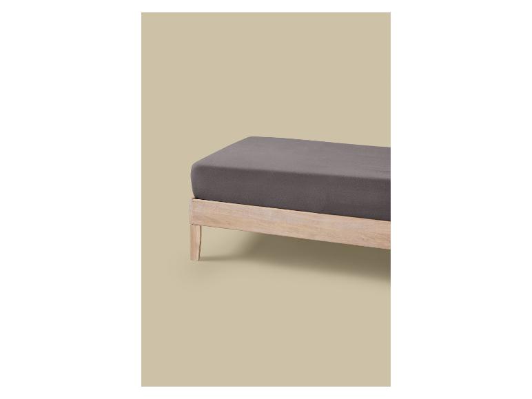 Un lit avec un cadre en bois clair et un matelas gris foncé.