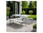 Table de pique-nique pliante blanche avec deux bancs sur une terrasse de jardin.