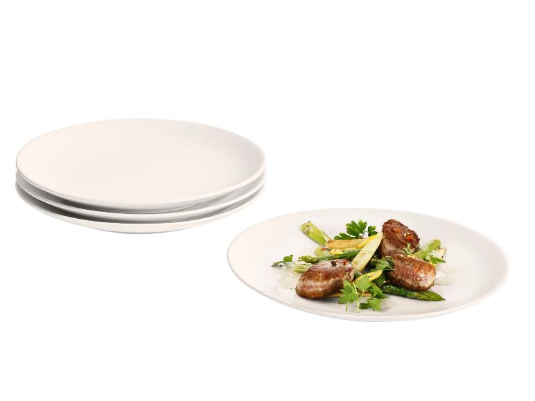 Assiettes blanches empilées et une assiette avec filet de bœuf, asperges et mini-épis de maïs.