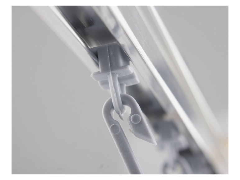 Gros plan sur des attaches de rideaux grises fixées à un rail en aluminium.