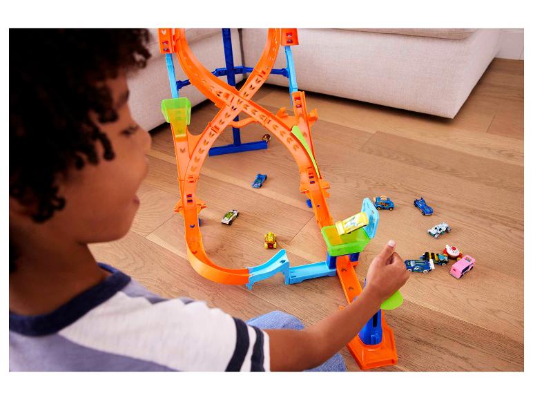 Enfant jouant avec une piste Hot Wheels avec plusieurs voitures et boucles.