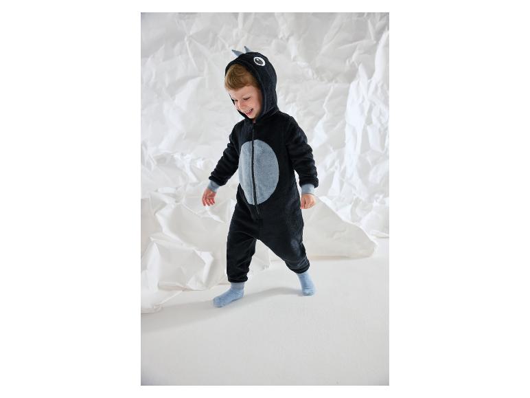 Garçon souriant dans une combinaison en peluche noire avec des détails gris.