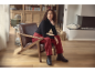 Femme en col roulé noir et pantalon rouge assise dans un fauteuil de salon.