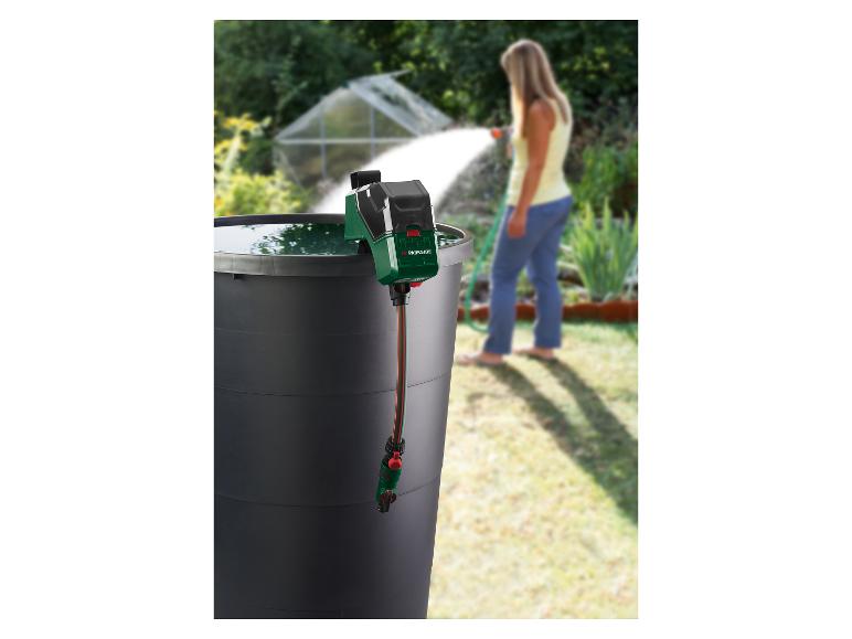 Pompe à eau de jardin dans un baril, femme arrosant le jardin.