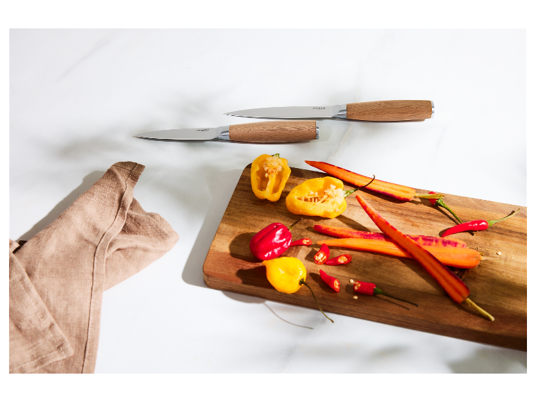 Couteaux de cuisine SilverCrest et légumes coupés sur une planche à découper en bois.