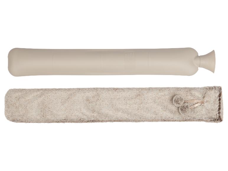 Une longue bouillotte beige et une housse moelleuse beige avec des pompons.