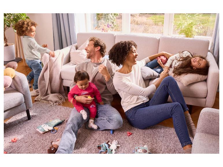 Une famille joue à la maison, entourée de jouets pour bébés.
