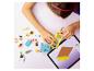 Enfant construisant une voiture jouet avec des blocs colorés, guidé par une tablette.