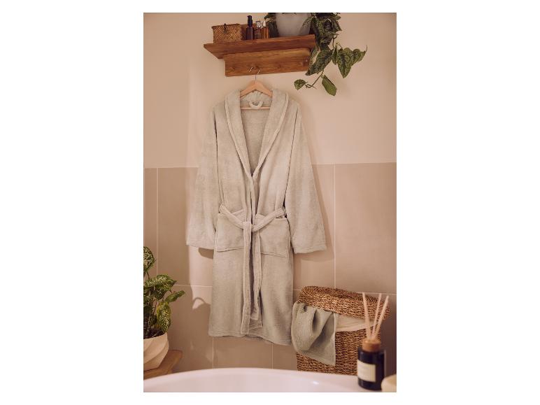 Peignoir gris dans une salle de bain avec plantes et panier en osier.