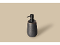 Distributeur de savon en céramique gris foncé avec pompe noire sur fond beige clair.