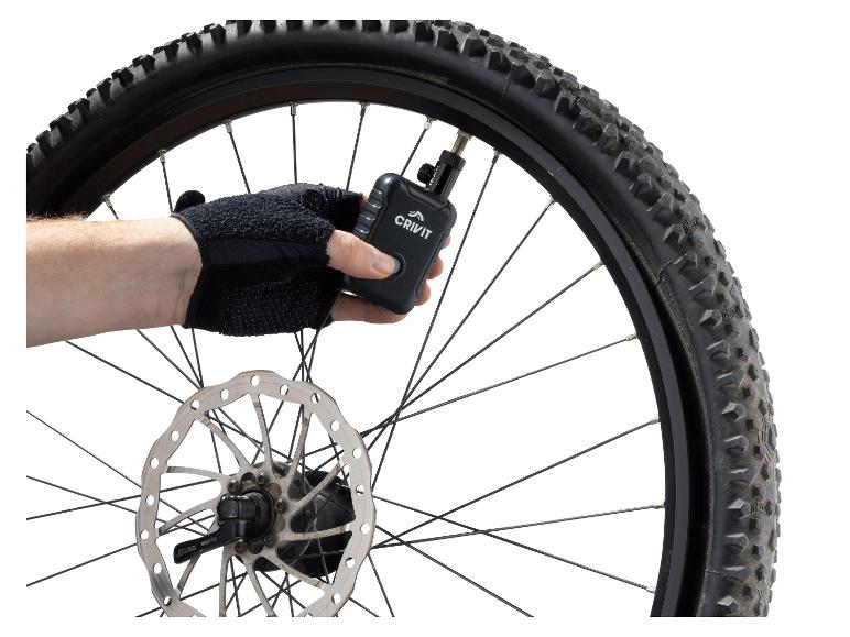 Main gantée gonflant un pneu de vélo Crivit avec une pompe à air numérique.
