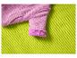 Manche tricotée rose avec manchette moelleuse sur un tissu vert texturé
