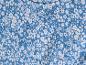 Un tissu bleu avec un petit motif de fleurs blanches.
