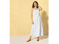 Une femme portant une robe blanche à bretelles fines et des sandales.