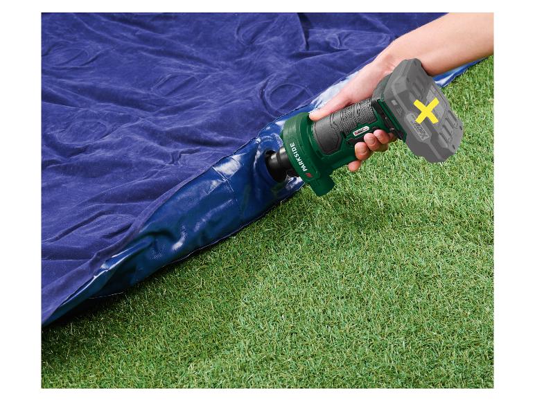 Pompe à air électrique gonflant un matelas pneumatique bleu sur l'herbe verte.