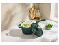 Marmite verte avec couvercle, remplie de soupe, sur un comptoir en marbre blanc.
