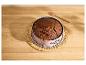Gâteau au chocolat dans un moule à charnière rose sur une natte en osier, avec un pinceau de cuisine.