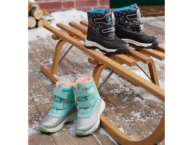 Des bottes de neige noires et bleu clair sur un traîneau en bois.