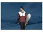 Un homme portant une veste Mountain Warehouse et une casquette tient une planche de snowboard devant des montagnes.