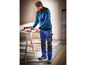 Homme portant des vêtements de travail bleus avec des détails noirs et des poches à outils
