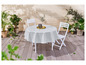 Une nappe ronde blanche sur une terrasse en bois avec deux chaises blanches.