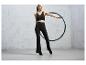 Une femme en tenue de sport noire avec un hula hoop bleu.