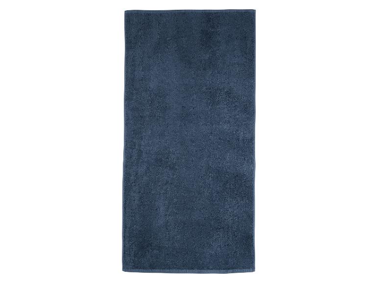 Une serviette de bain bleu foncé pliée sur un fond blanc.