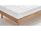 Un matelas blanc avec une texture ondulée sur un cadre de lit en bois.