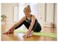 Femme en tenue de sport Jette Sport faisant du yoga sur un tapis vert.
