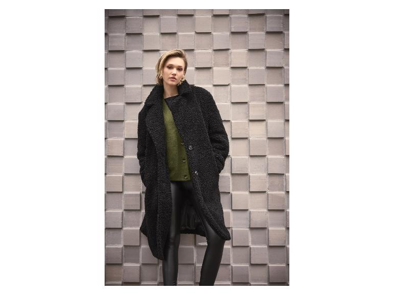 Femme en manteau teddy noir, cardigan vert et pantalon en cuir
