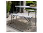 Table et bancs de jardin pliants gris sur une terrasse avec une plante et un tapis.