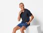 Homme en t-shirt bleu foncé avec poche et short à carreaux bleus.