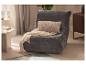 Fauteuil de sol en velours gris avec coussin et plaid crème, à côté d'une table d'appoint.