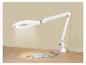 Lampe loupe blanche avec accessoires de couture sur une table en bois.