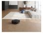 Robot aspirateur nettoyant un sol en bois dans un salon moderne avec canapé et tapis.
