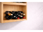 Étagère en bois avec un casier à vin ondulé noir contenant six bouteilles.