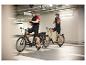Deux cyclistes avec vélos électriques dans un parking.